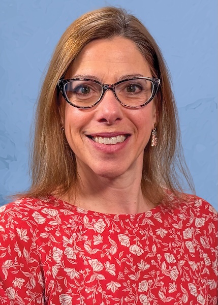 Headshot of a smiling woman in glasses and a red-print shirt. 