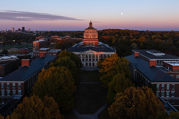 An aerial view of Rush Rhees Library at sunset with downtown Rochester in the background.