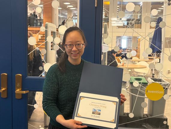 Photo of Christina Wang holding her Undergraduate Research Initiative Award.