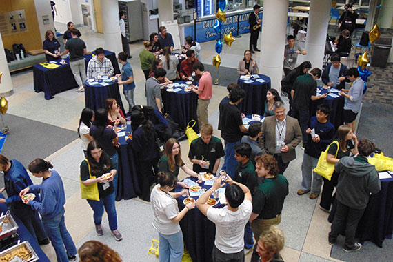 A crowd gathers and eats hors d'oeuvres in the Goergen Hall atrium.