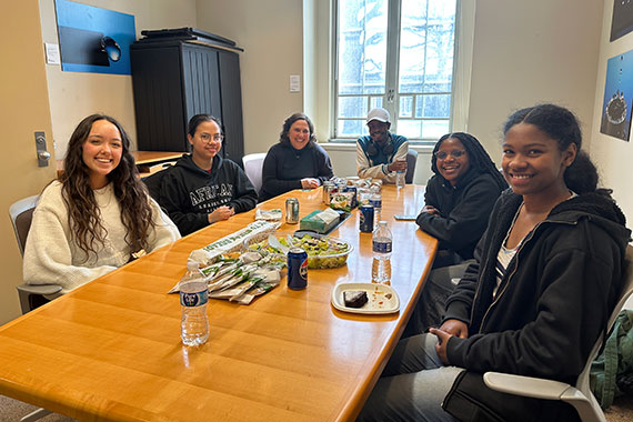 Dean Heinzelman and five students gather for lunch in a conference room.