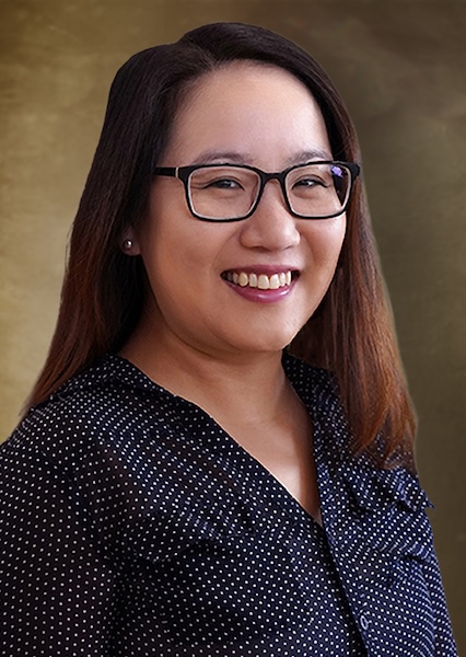 Headshot of a smiling woman with long brown hair in glasses. 