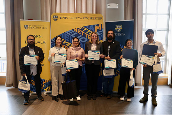 Seven studies pose with certificates at the Graduate Research Day awards ceremony.