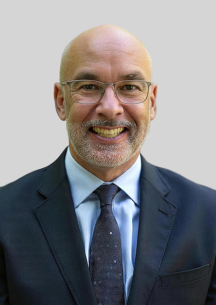 man with glasses wearing a dark suit and tie.