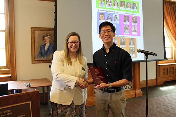 A student shakes a faculty member's hand while receiving an award at the Rush Rhees Library.