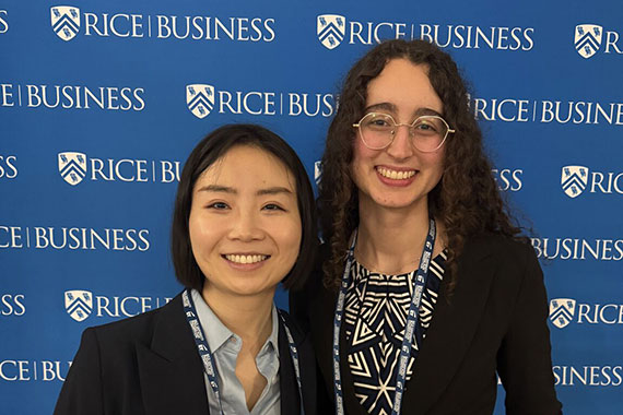Two Hajim graduate students pose in front of a Rice Business backdrop.