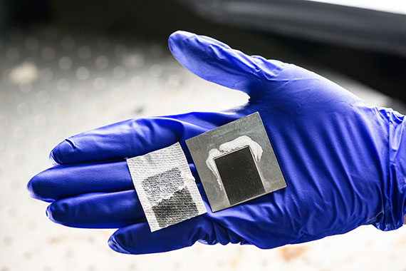 A blue glove holding two solar-thermal desalination devices.