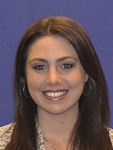 Smiling woman with brown hair against a purple background. 