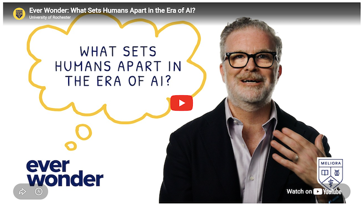 YouTube video screen with a professor in a button-down shirt and dark blazer. A thought bubble reads: What sets humans apart in the era of AI?