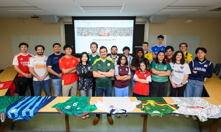 A professor with students wearing soccer jerseys.