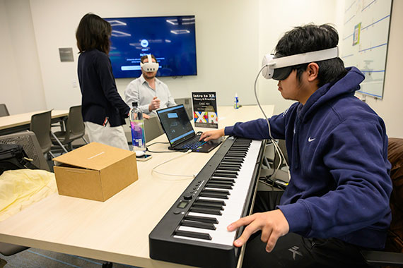 A student plays a keyboard while wearing a VR headset.
