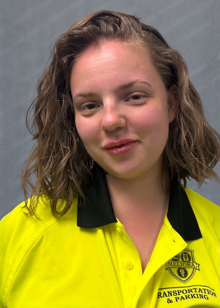Employee with shoulder-length brown hair in a yellow Parking Services shirt.