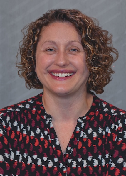 Smiling woman in patterned shirt. 