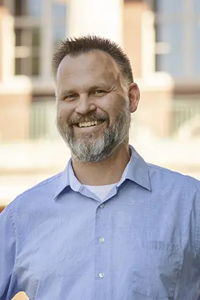 Smiling man in light blue shirt. 