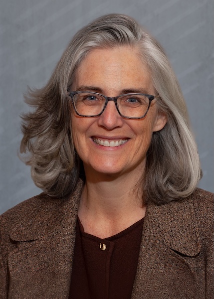 Smiling woman in glasses wearing a brown blazer. 