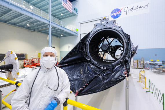 A person in a clean suit stands in front of the Nancy Grace Roman Space Telescope.