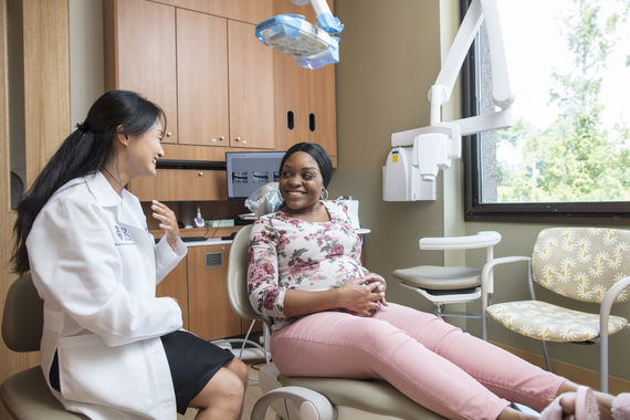 Jin Xiao speaks to a patient sitting in a chair in a dentist office.