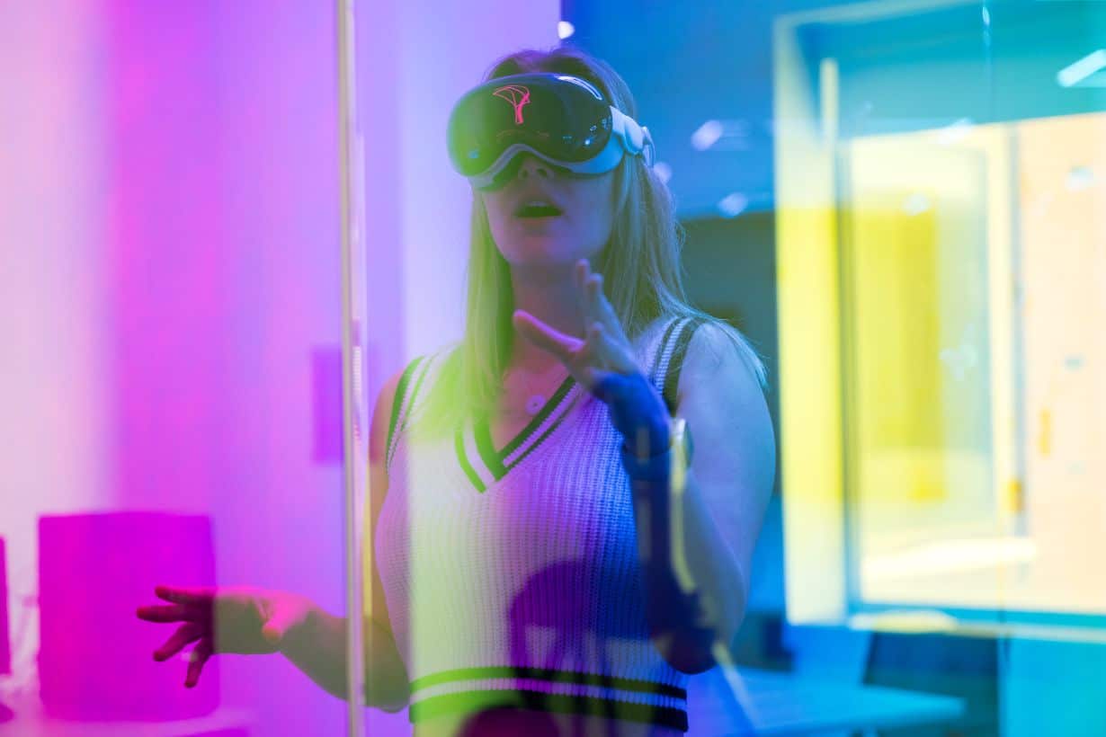 Person wearing a virtual reality headset in a room with colorful lighting.