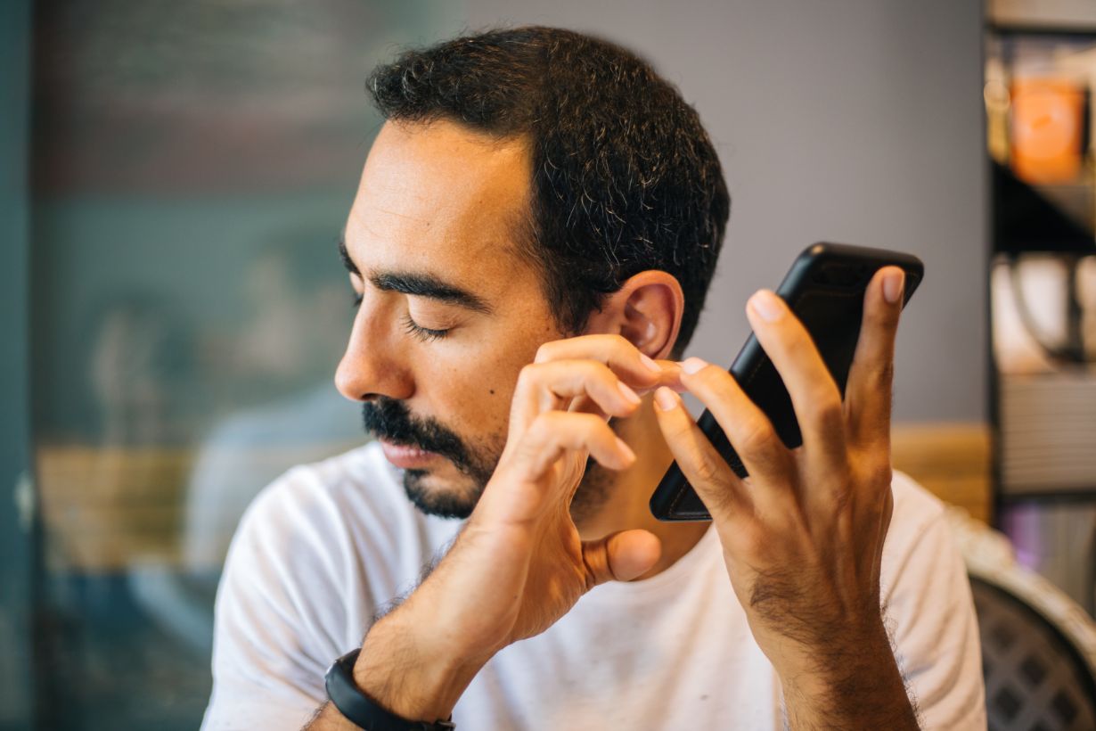 Man holding a smartphone to his ear with eyes closed.
