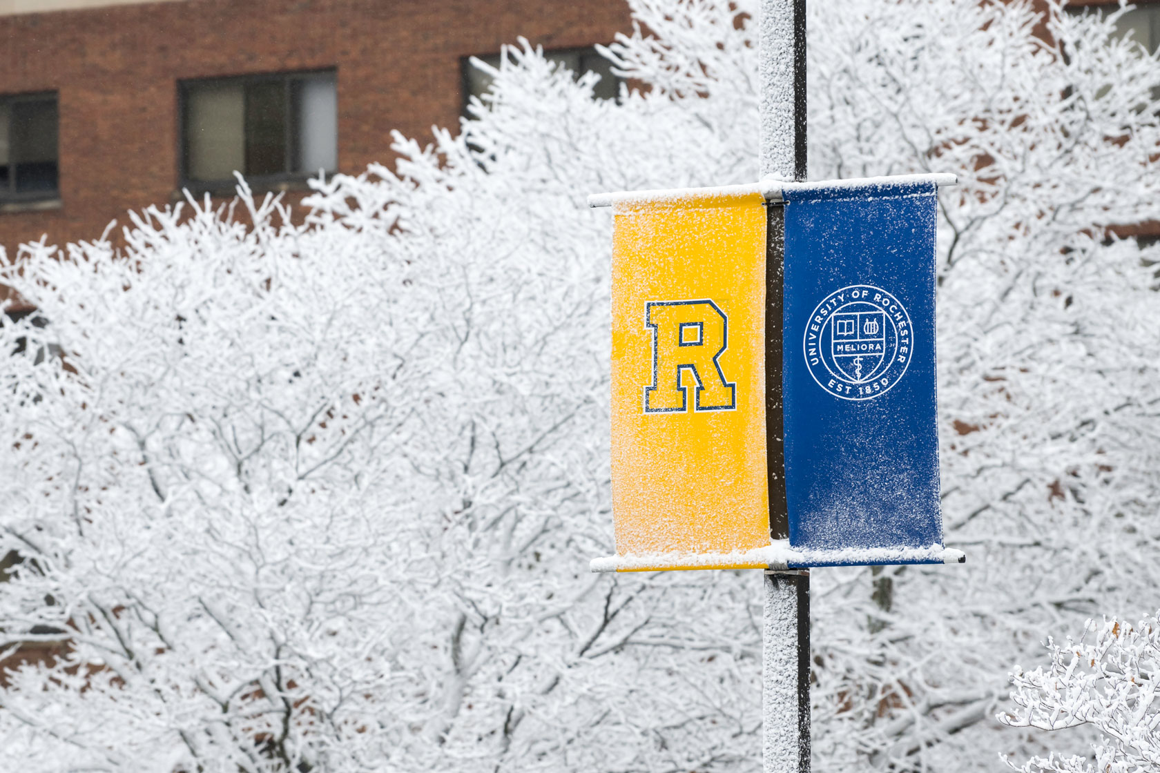 A street sign in front of the University of Rochester building, showcasing the campus environment.