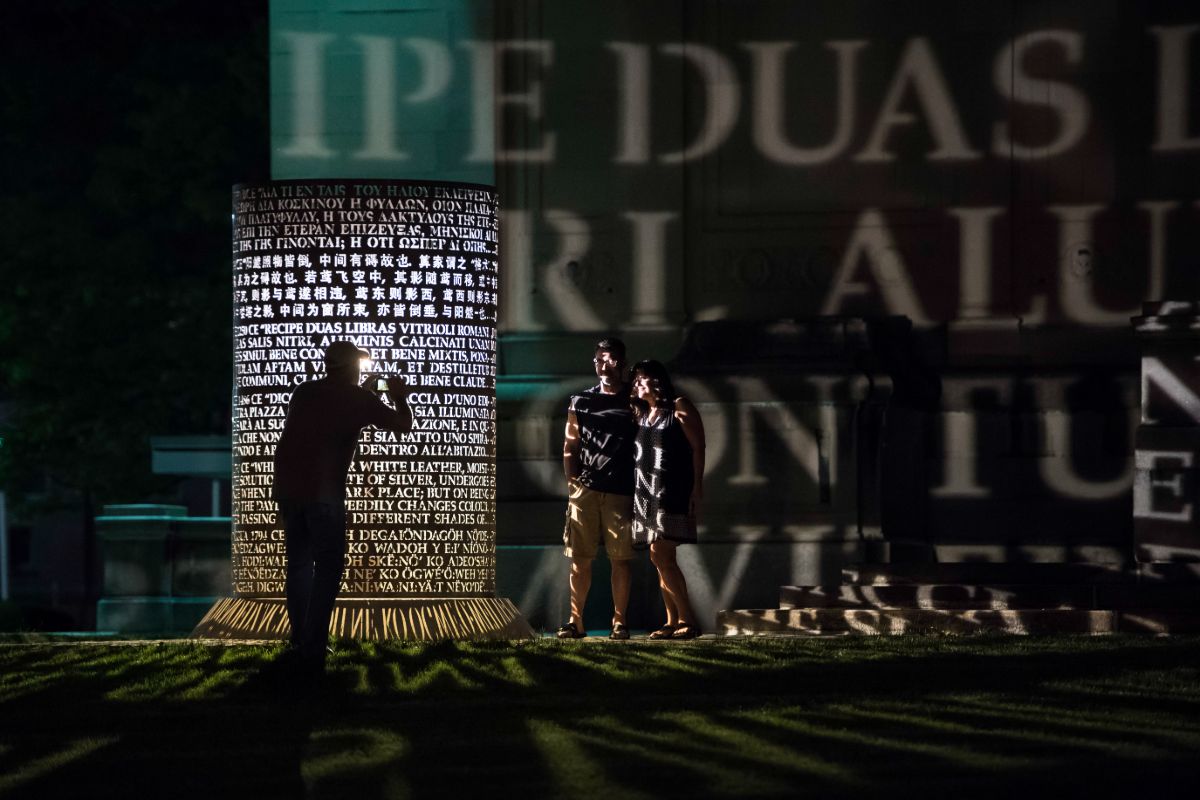 A man and woman stand before a large illuminated sculpture at the University of Rochester's Memorial Art Gallery.
