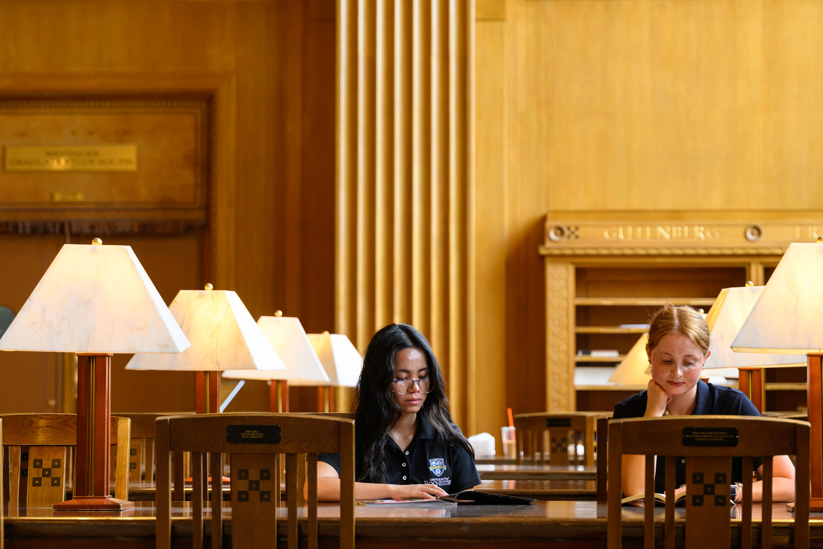 Two students studying together at a table in the University of Rochester library.