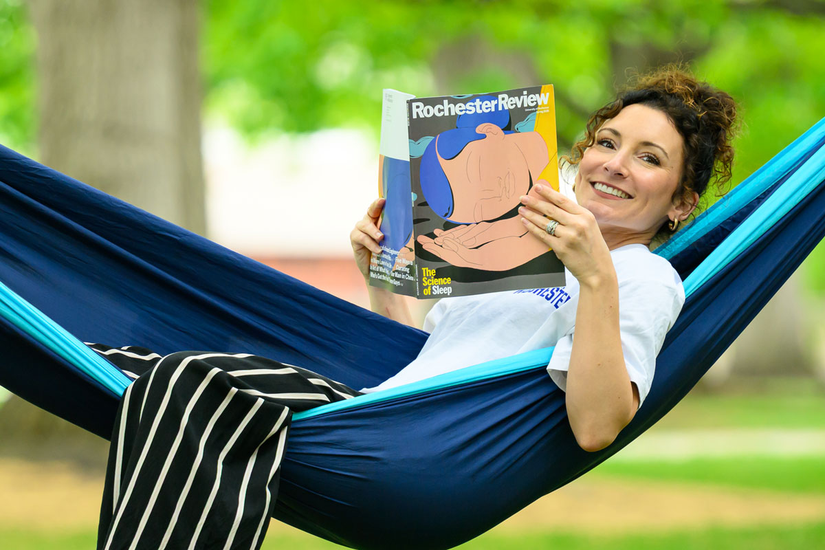 A woman relaxes in a hammock, reading the University of Rochester's magazine, Rochester Review.