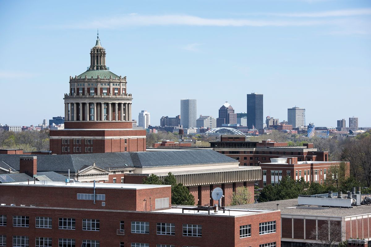 Rush Rhees Library on the University of Rochester’s River Campus, with the Rochester skyline in the distance.