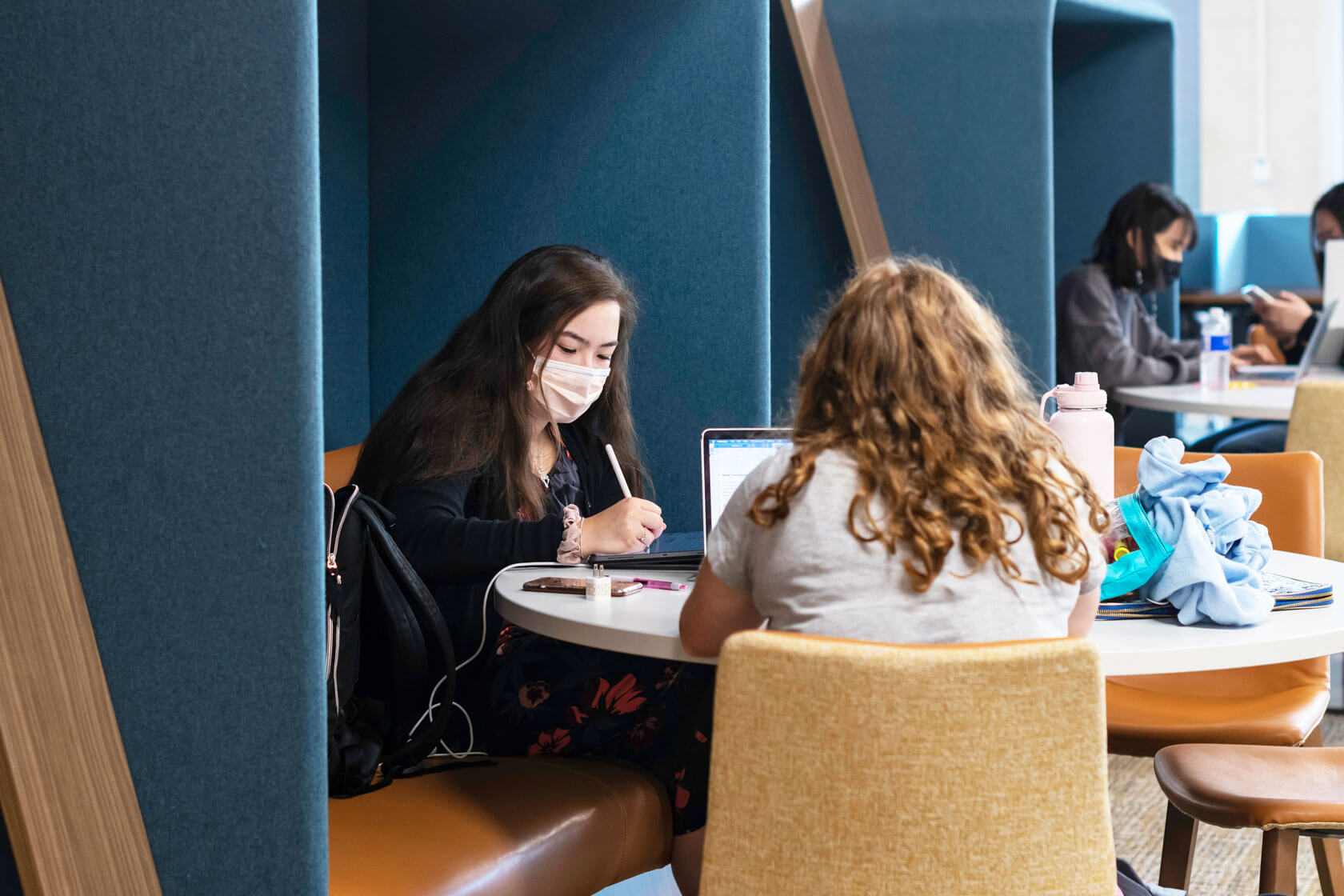 University of Rochester students working while wearing a mask.
