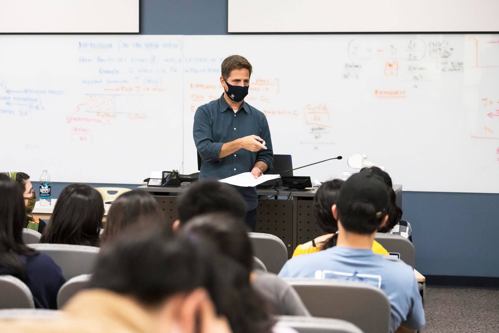 University of Rochester Professor teaches classroom of students while wearing a mask.