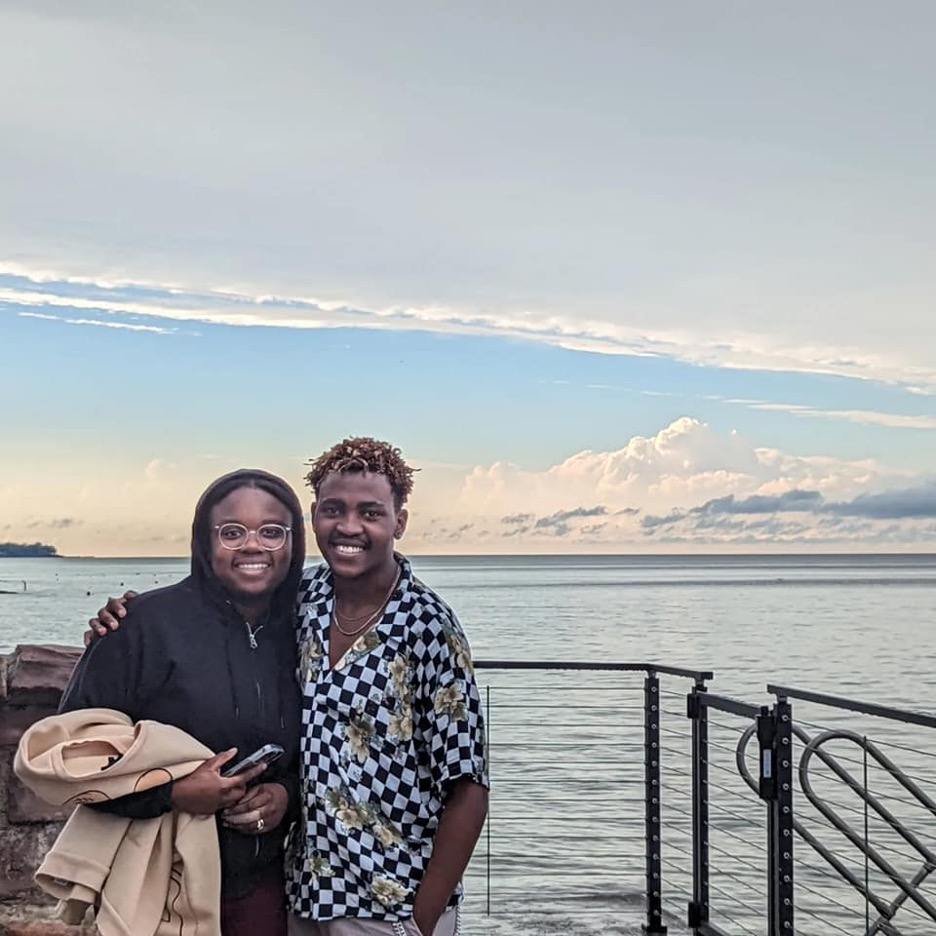 Two people standing on a deck with the lake in the background.