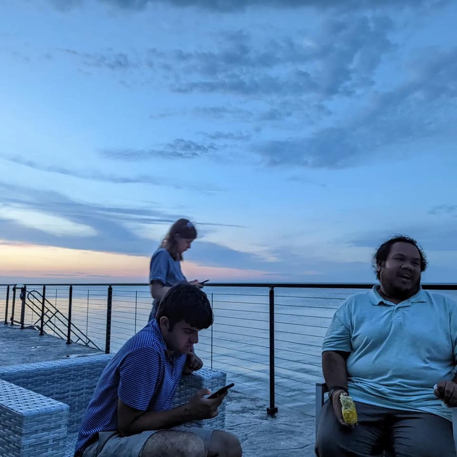 Three students on a deck with the lake in the background.
