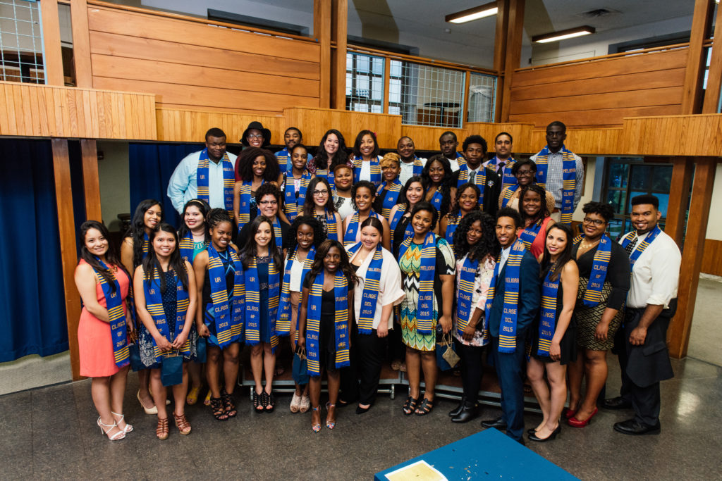 A University of Rochester student organization, group of students smiling for the camera wearing special graduation robes