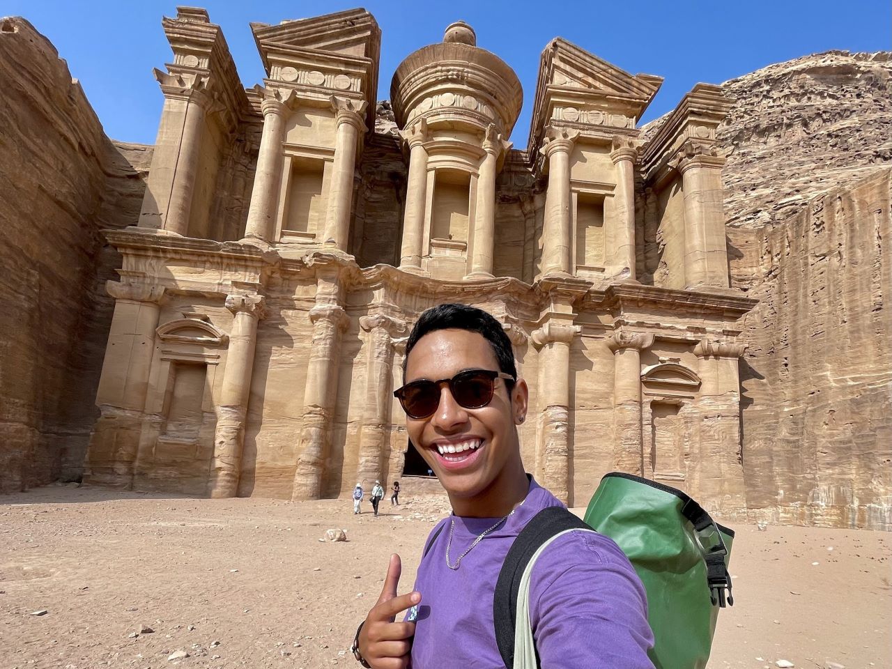 A student taking a selfie in front of a building in the desert of Petra, Jordan