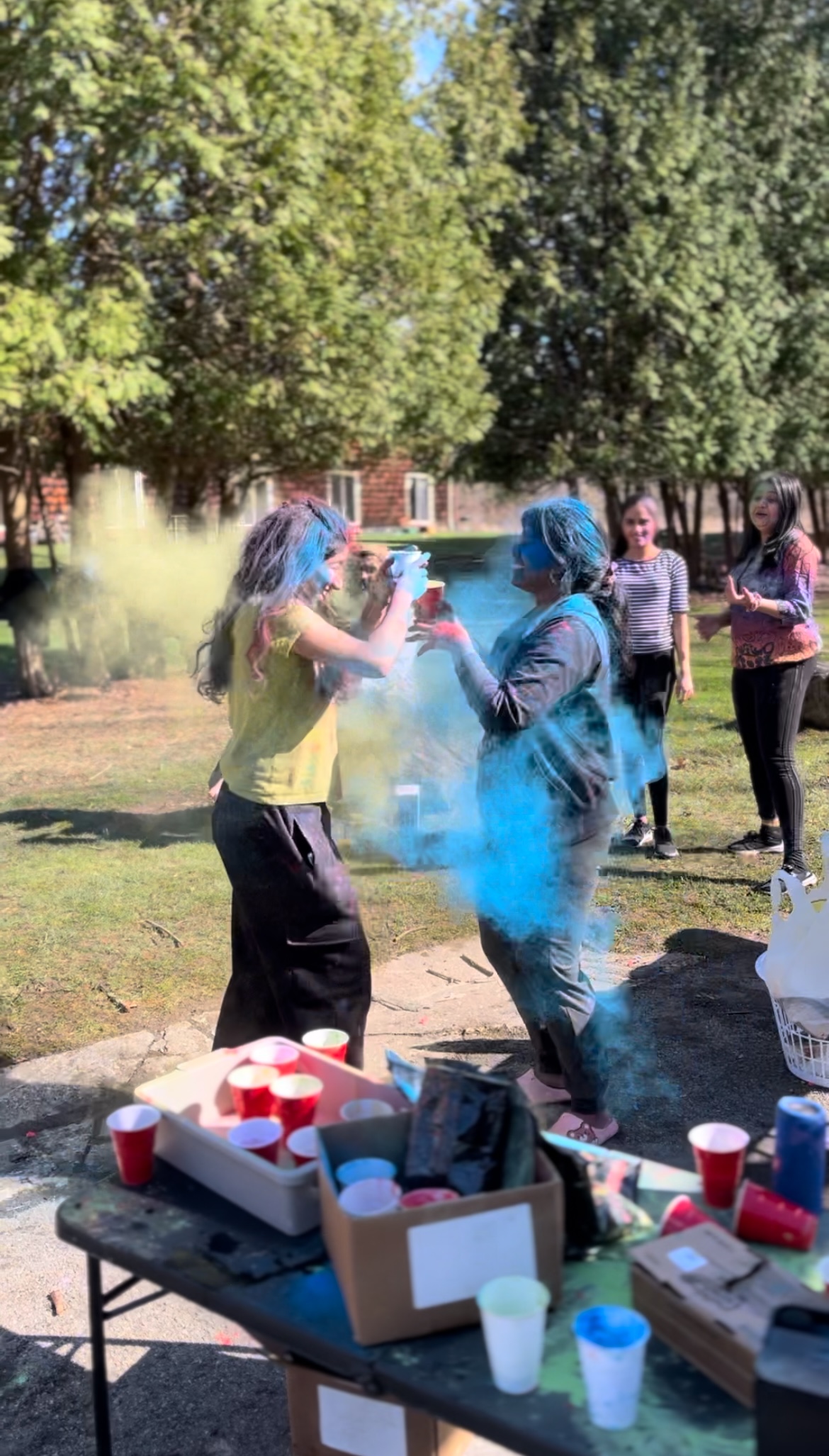 Two students splashing each other with colored powder during a campus event