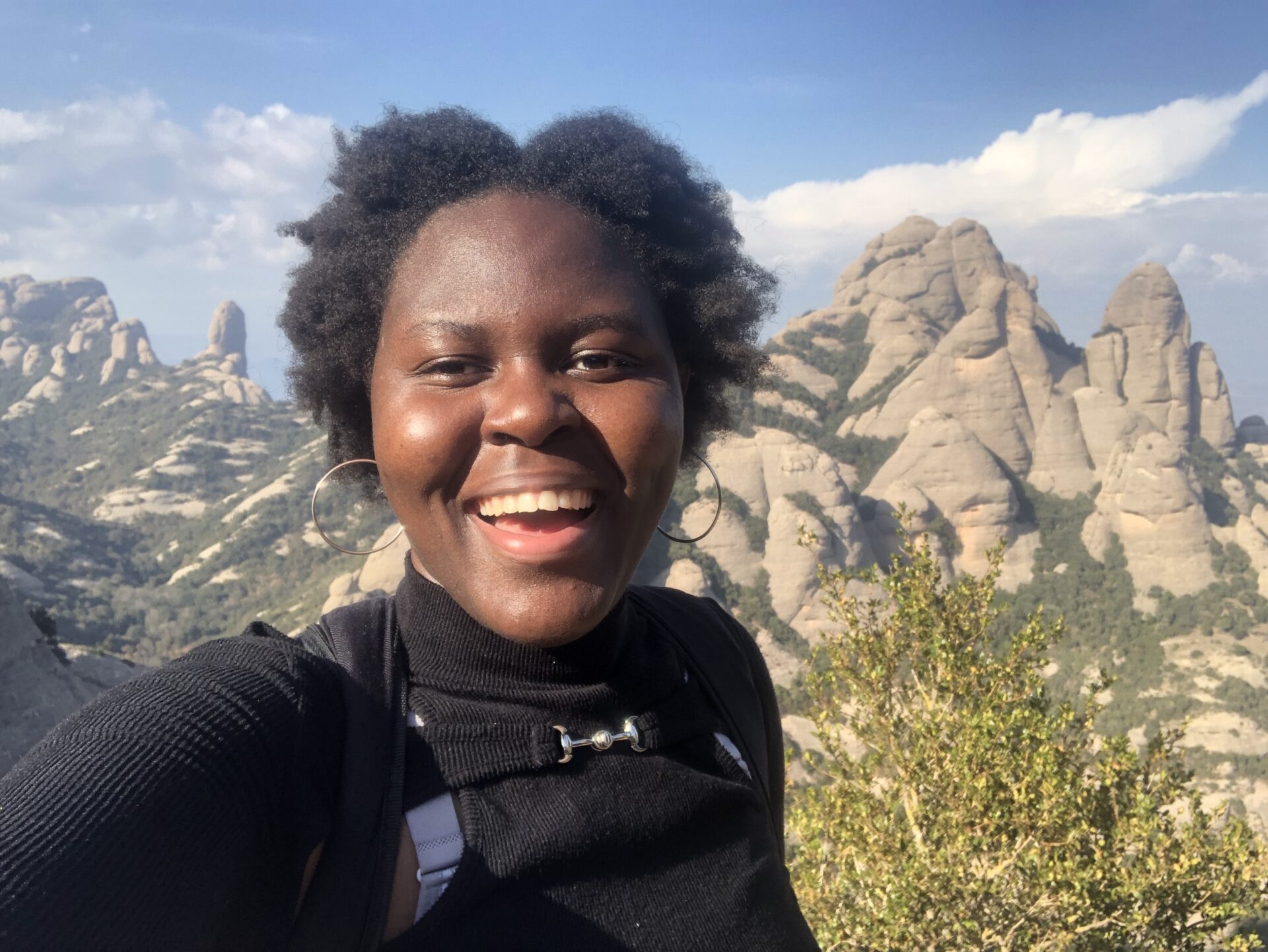 A student takes a selfie in front a mountain range while hiking