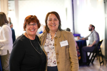 Two women pose together at the George Eastman Circle Faculty & Staff Reception held on March 19, 2025.