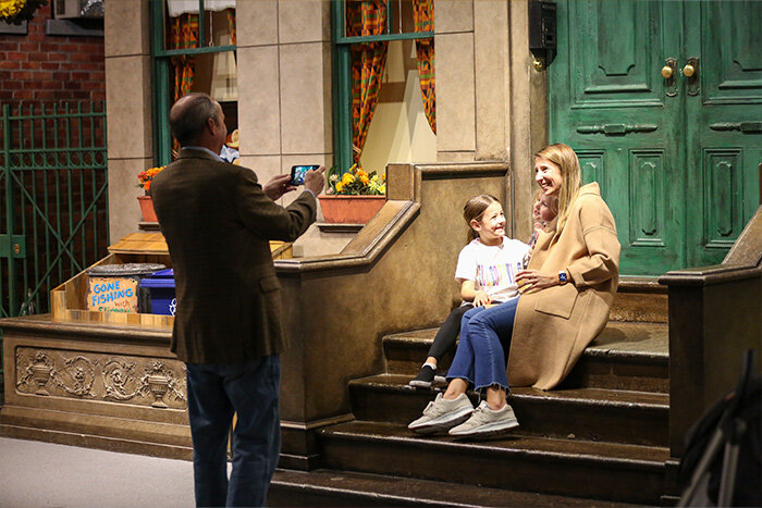 A woman and girl taking a photo in front of Sesame street step in Museum of Play