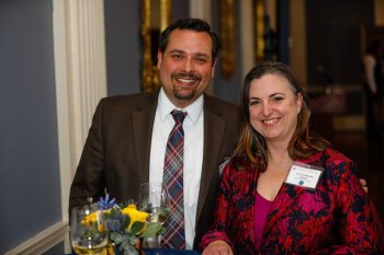 A man and woman pose for a photo at the George Eastman Circle Faculty & Staff Reception held on March 30, 2023 within Rochester New York.