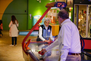 An older woman and man play air hockey at the George Eastman Circle Family Celebration, held on April 27, 2023 within Rochester New York.