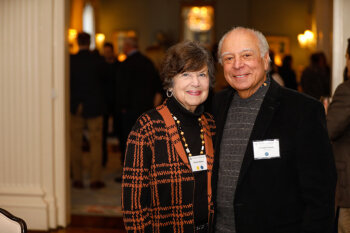 A man and woman pose for a photo at the George Eastman Circle Faculty & Staff Reception held on March 30, 2023 within Rochester New York.