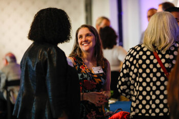 A woman smiles while chatting with fellow attendees at the George Eastman Circle Faculty & Staff Reception in Rochester, NY.
