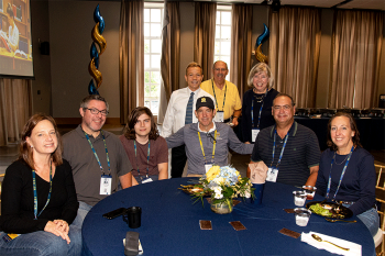 Group photo of people seated at a table posing for photo