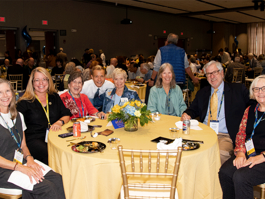 Group of people seated at table posing for a photo