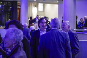 3 men having a conversation during reception in MAG lobby