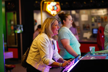 A candid photo of a female playing a racing arcade game at the George Eastman Circle Family Celebration, held on April 27, 2023 within Rochester New York.