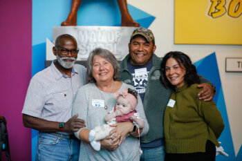 Four individuals pose as a baby is being held for a group photo at the George Eastman Circle Family Celebration, held on April 27, 2023 within Rochester New York.