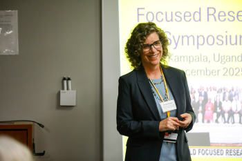 A woman speaking with a slide deck projecting in the background