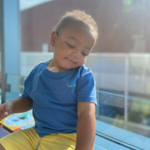 A photo of a young child name noah, in a blue shirt and yellow shorts