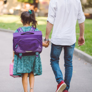 A father walking his young daughter to school, holding hands